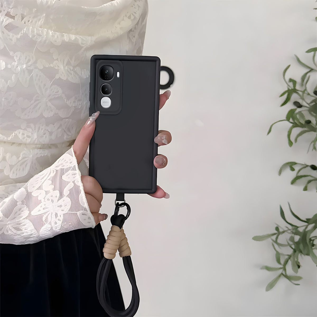 Person holding a black phone case with a lanyard on a light background